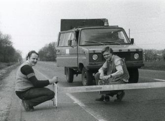 Pracownicy wykonujący pomiary na drodze dwupasmowej, w tle samochód Tarpan ze specjalistyczną zabudową badawczą – lata 80.