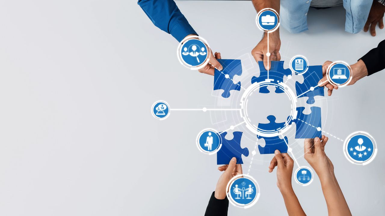 Dłonie trzymające niebieskie puzzle, składają się one w całość – grafika ilustracyjna