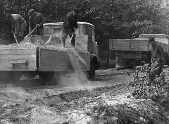 Pracownicy wysypują łopatami kruszywo z ciężarówki – lata 60.