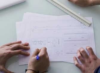 Dłonie nad kartką z projektem – grafika ilustracyjna.