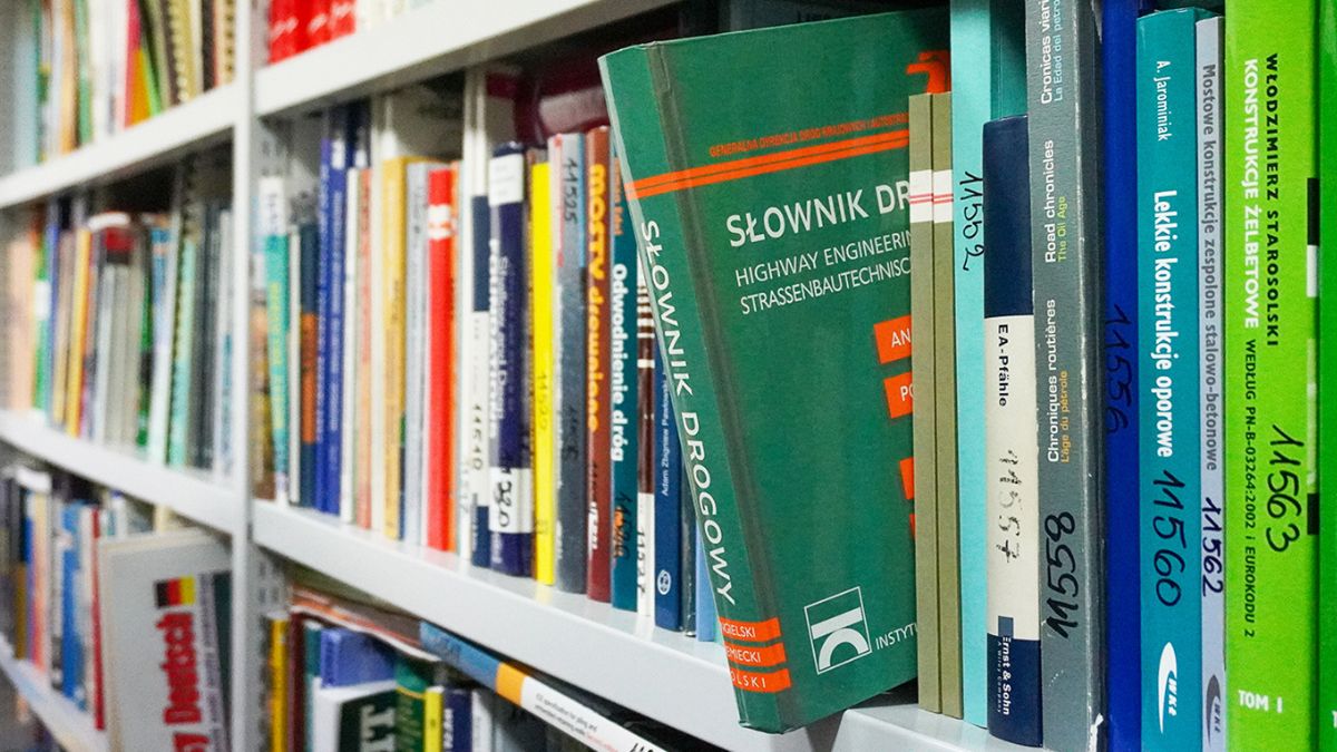 Półka z wieloma książkami, jedna z nich „Słownik drogowy” wystaje z półki.