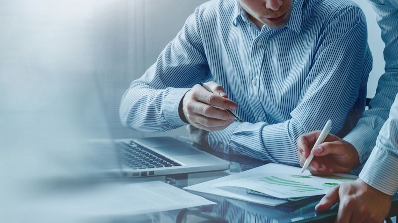 grafika przedstawiająca dwie osoby analizujące wykresy wydrukowane na kartce papieru, przy otwartym laptopie